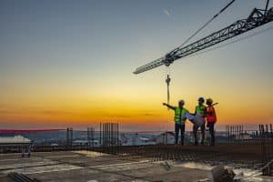 Multi ethic workers talking at construction site reviewing plans