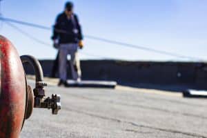 Roll roofing Installation with propane blowtorch during construction works