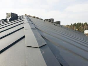 close up view of grey folding roof and chimney on waterproofing layer of house under construction