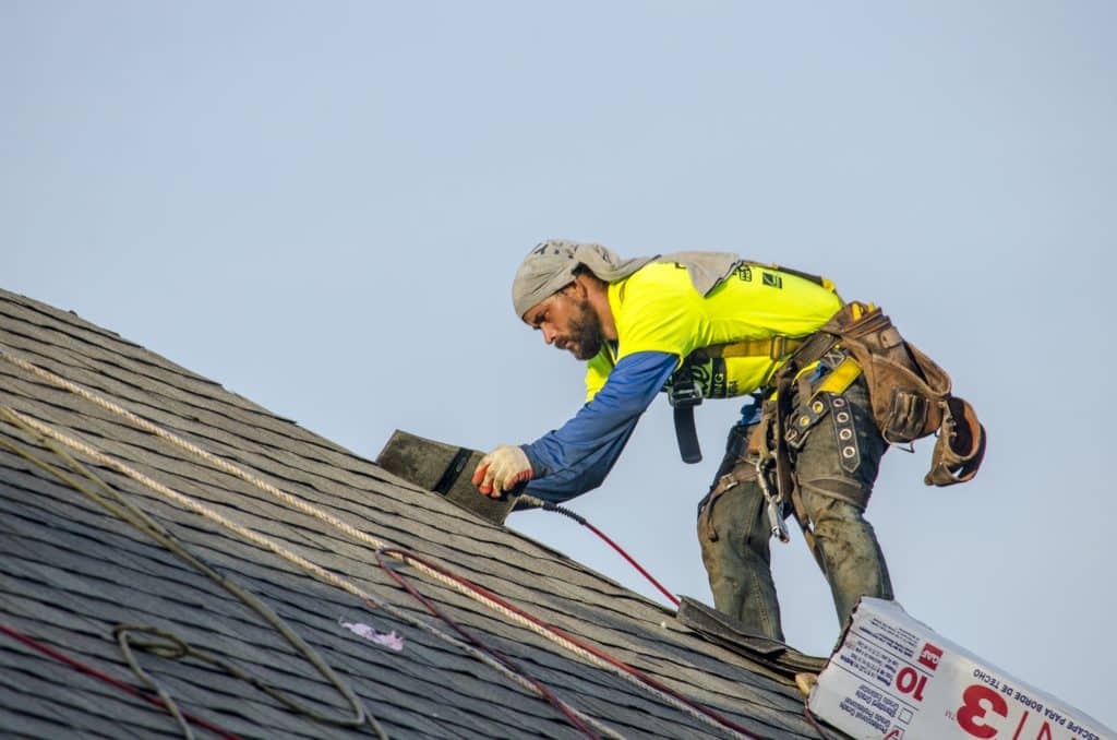 A professional roofer fixing a roof with hail damage.