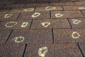 A haild damged roof has areas of damaged marked with a white circle