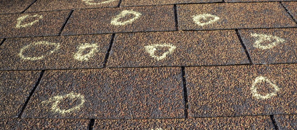 A haild damged roof has areas of damaged marked with a white circle