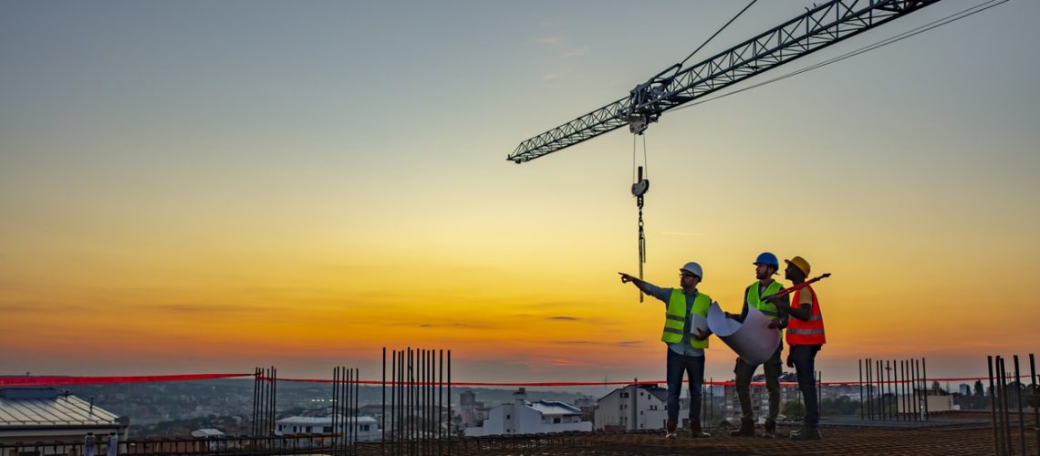 Multi ethic workers talking at construction site reviewing plans