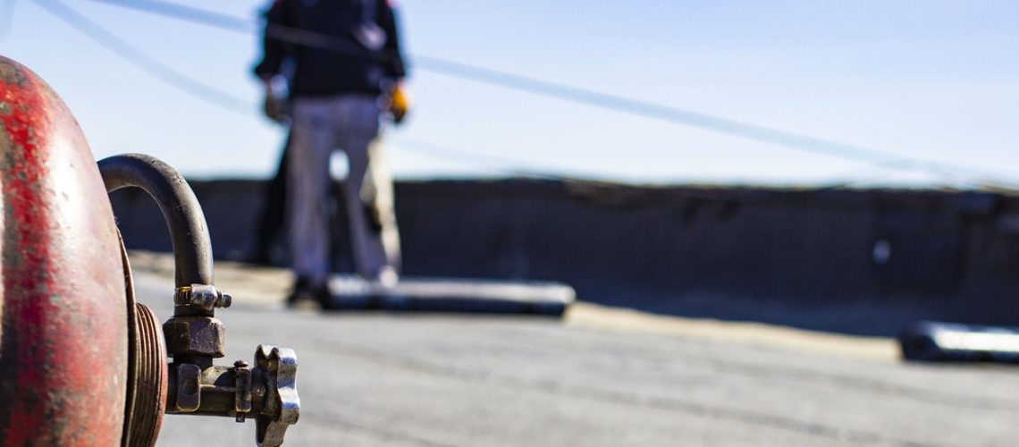 Roll roofing Installation with propane blowtorch during construction works