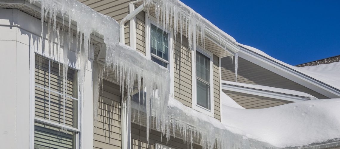 Ice dams and snow on roof and gutters after bitter cold in New England, USA